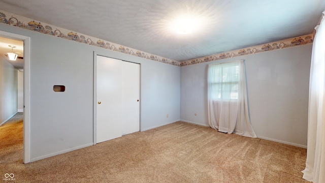 unfurnished bedroom with light carpet, baseboards, and a closet