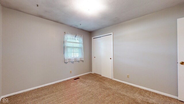 unfurnished bedroom with carpet flooring, a closet, and baseboards