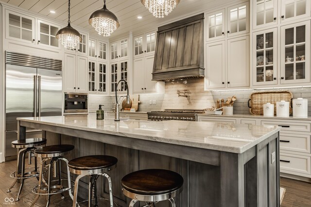 6734 W Stonegate Dr, Zionsville, IN 46077 - kitchen featuring stainless steel appliances, custom exhaust hood, a chandelier, dark wood-type flooring, and white cabinetry