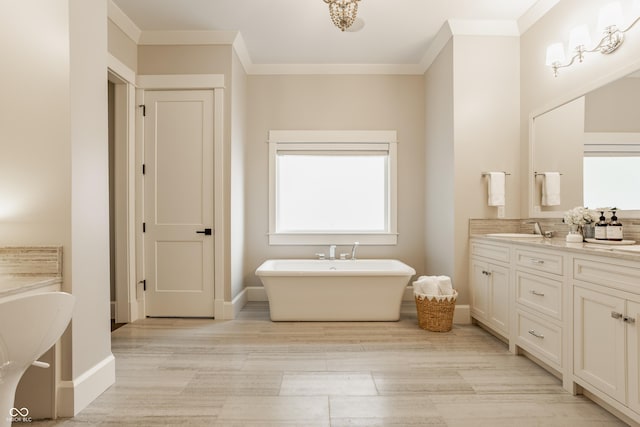 6734 W Stonegate Dr, Zionsville, IN 46077 - bathroom featuring wood finished floors, a freestanding tub, vanity, crown molding, and baseboards