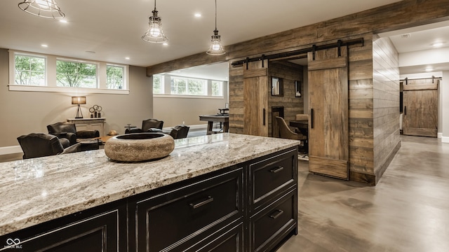 6734 W Stonegate Dr, Zionsville, IN 46077 - kitchen featuring a barn door, dark cabinets, open floor plan, light stone counters, and recessed lighting