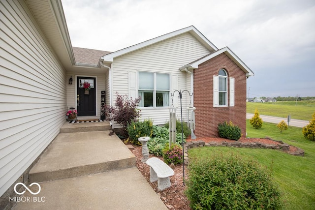 property entrance featuring a yard and brick siding
