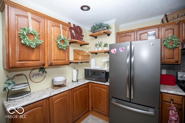 kitchen with freestanding refrigerator, black microwave, crown molding, open shelves, and brown cabinets