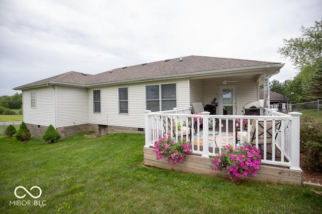 rear view of property with a lawn, a deck, and a shingled roof