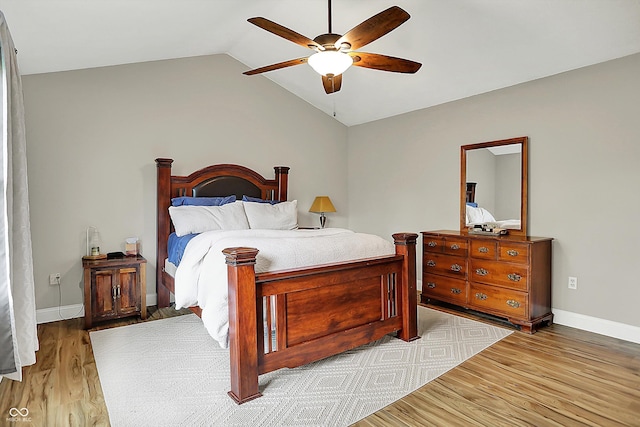 bedroom featuring wood finished floors, lofted ceiling, baseboards, and a ceiling fan