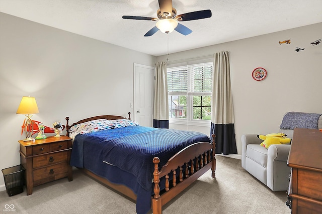bedroom featuring light colored carpet, baseboards, a ceiling fan, and a textured ceiling