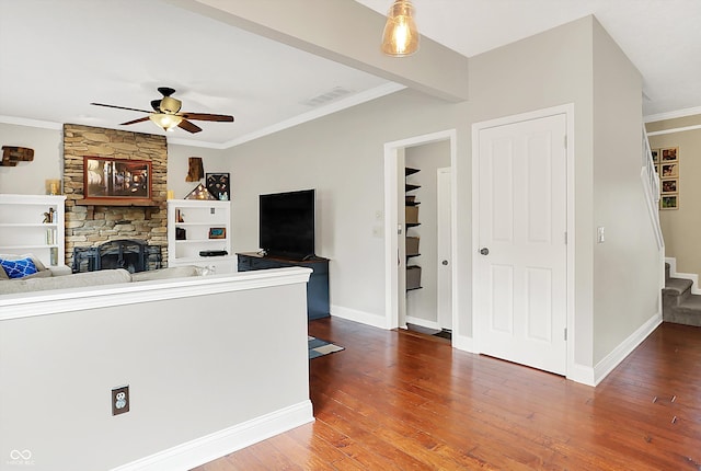 living area with stairway, ceiling fan, wood finished floors, a fireplace, and ornamental molding