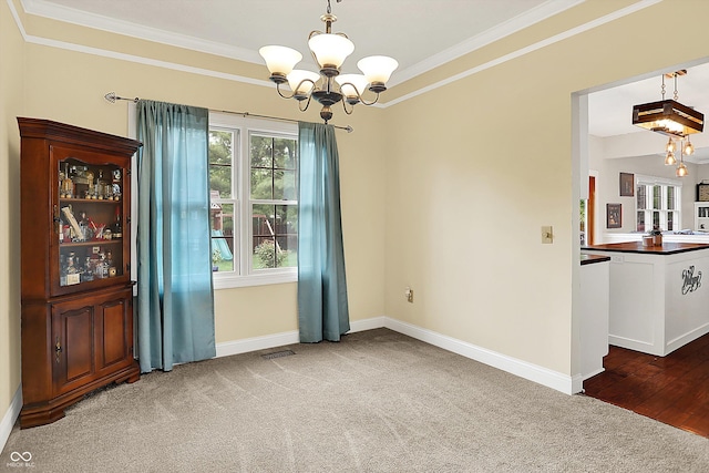unfurnished dining area with a chandelier, ornamental molding, carpet, and baseboards
