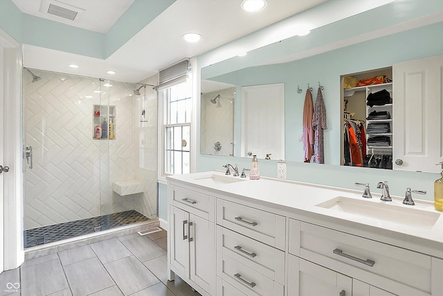 bathroom featuring a shower stall, double vanity, recessed lighting, and a walk in closet