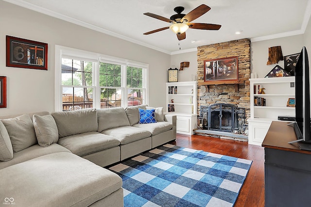 living area with a ceiling fan, ornamental molding, dark wood-style floors, and a stone fireplace