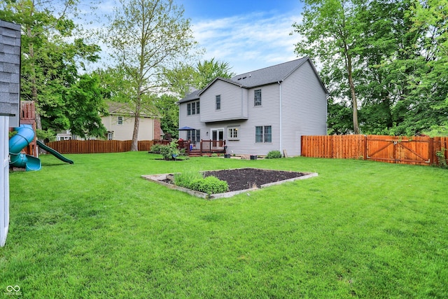 view of yard featuring a deck, a playground, and a gate