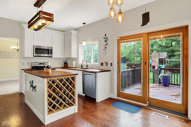 kitchen featuring appliances with stainless steel finishes, a sink, wooden counters, white cabinetry, and dark wood-type flooring
