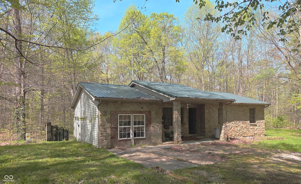 view of front of home featuring stone siding, a front lawn, and metal roof