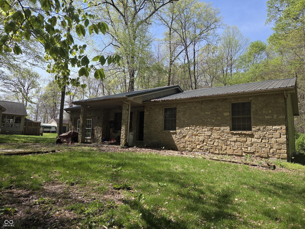 view of front of property featuring stone siding, a front lawn, and metal roof