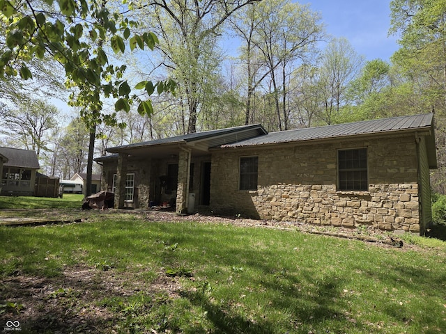 view of front of property featuring stone siding, a front lawn, and metal roof