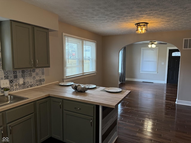 3720 W 16th St, Indianapolis, IN 46222 - kitchen with butcher block countertops, arched walkways, a peninsula, a textured ceiling, and tasteful backsplash