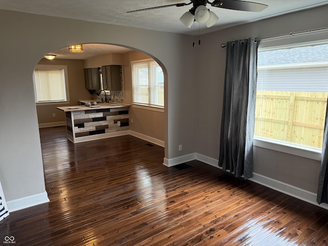 3720 W 16th St, Indianapolis, IN 46222 - unfurnished room with ceiling fan, arched walkways, baseboards, and dark wood-style floors