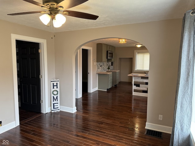 3720 W 16th St, Indianapolis, IN 46222 - spare room with arched walkways, baseboards, ceiling fan, and dark wood-style flooring