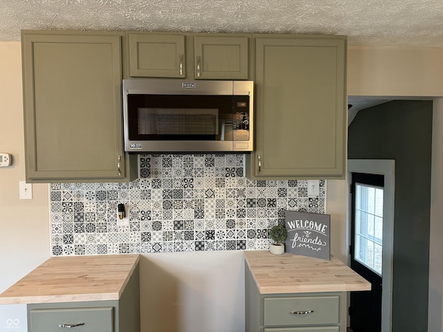 3720 W 16th St, Indianapolis, IN 46222 - kitchen with stainless steel microwave, butcher block counters, green cabinets, decorative backsplash, and a textured ceiling