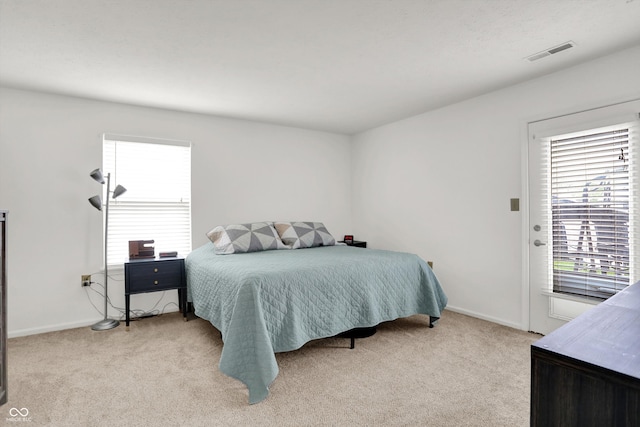 bedroom featuring light carpet, multiple windows, and baseboards
