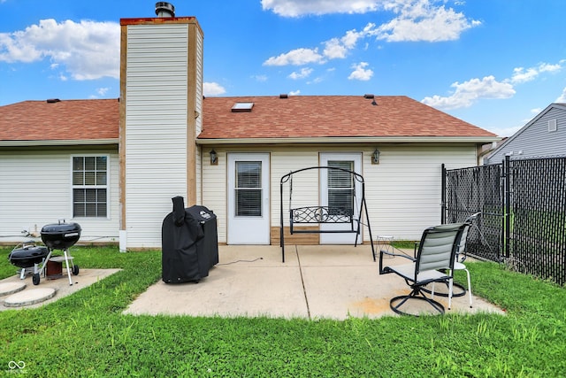 rear view of property featuring a chimney, a patio area, and a shingled roof
