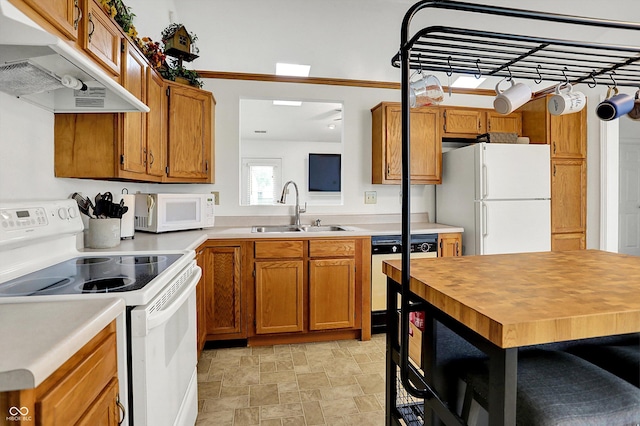 kitchen with white appliances, under cabinet range hood, a sink, and brown cabinetry