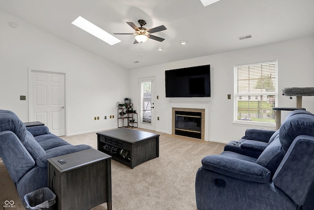 living area featuring a skylight, a ceiling fan, light carpet, plenty of natural light, and lofted ceiling