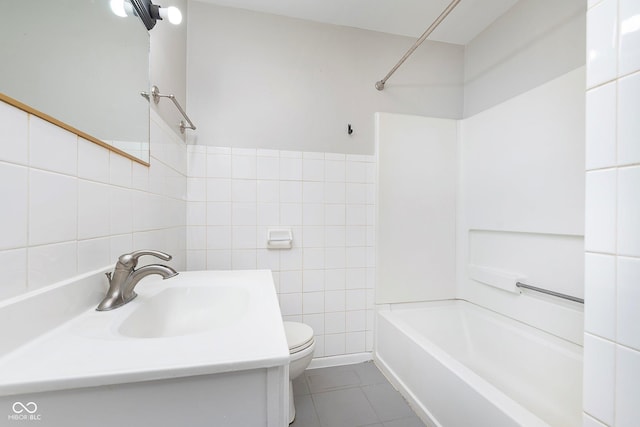 bathroom with tile walls, a sink, toilet, tile patterned flooring, and shower / washtub combination