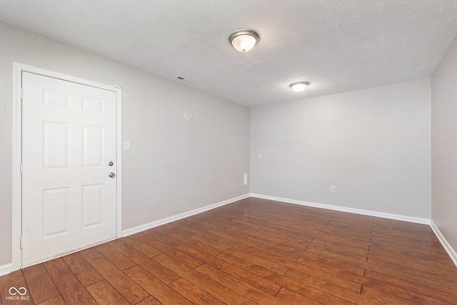 empty room featuring hardwood / wood-style flooring, baseboards, and a textured ceiling
