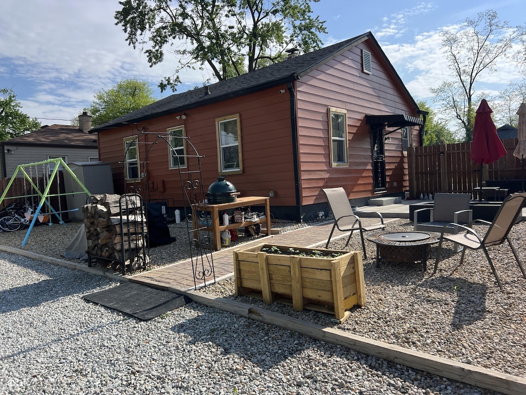 rear view of house featuring a fire pit, a patio, and fence