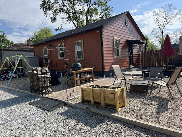rear view of house featuring a fire pit, a patio, and fence