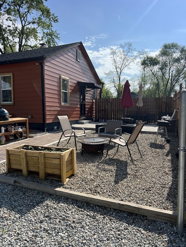 view of patio / terrace featuring an outdoor fire pit, fence, and a garden