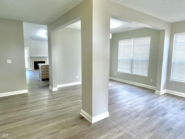 unfurnished living room featuring wood finished floors, healthy amount of natural light, and baseboards
