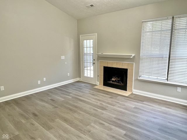 unfurnished living room with wood finished floors, baseboards, a textured ceiling, and a fireplace