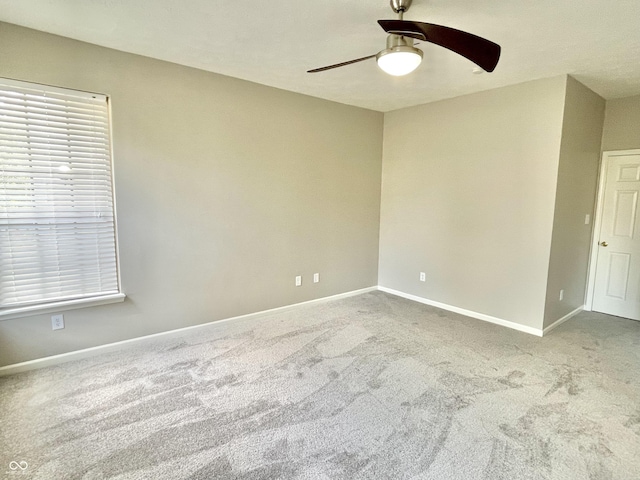 spare room with ceiling fan, carpet, and baseboards
