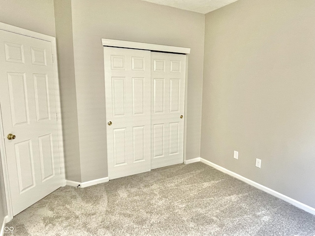 unfurnished bedroom with carpet flooring, baseboards, and a closet