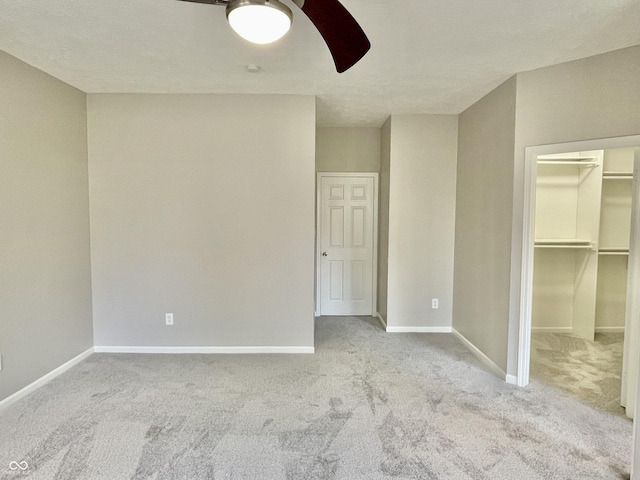 unfurnished bedroom with carpet flooring, a spacious closet, and baseboards