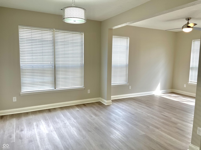 unfurnished room with wood finished floors, baseboards, and plenty of natural light