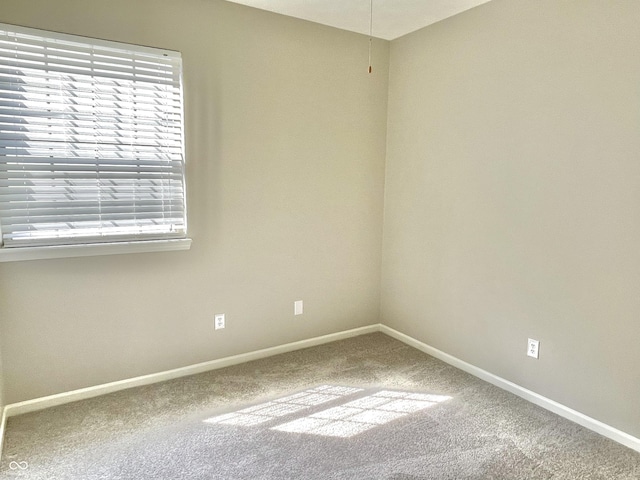 carpeted spare room featuring baseboards