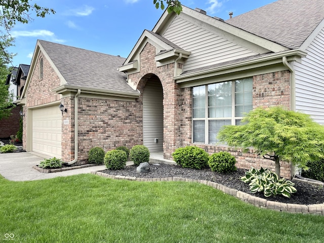 view of front facade with a shingled roof, brick siding, a front lawn, and concrete driveway