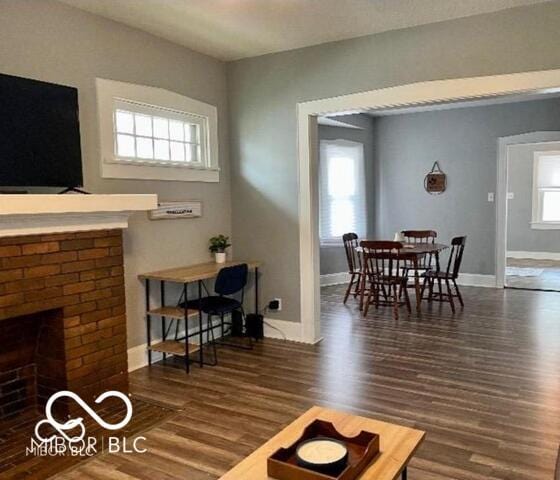 living area with wood finished floors, baseboards, and a brick fireplace
