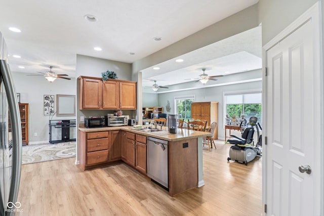 kitchen featuring stainless steel appliances, a peninsula, a ceiling fan, recessed lighting, and light wood-type flooring