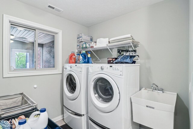 clothes washing area with washer and clothes dryer, baseboards, and a textured ceiling