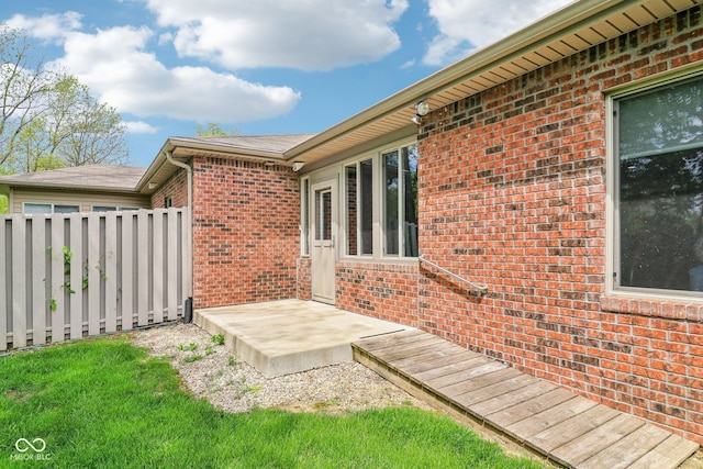 view of side of property featuring brick siding and fence