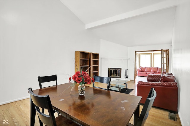 7642 Lancer Ln, Lawrence, IN 46226 - dining room featuring light wood finished floors, a fireplace, beamed ceiling, high vaulted ceiling, and baseboards
