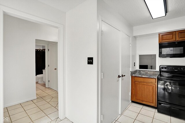 7642 Lancer Ln, Lawrence, IN 46226 - kitchen with black appliances, light tile patterned floors, and brown cabinetry