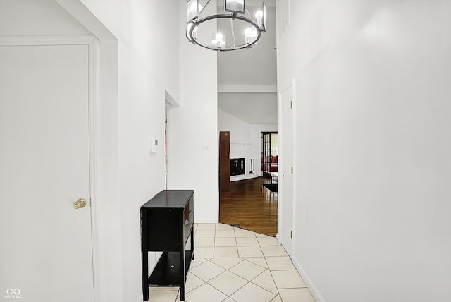 7642 Lancer Ln, Lawrence, IN 46226 - hallway featuring light tile patterned flooring, a towering ceiling, a chandelier, and baseboards