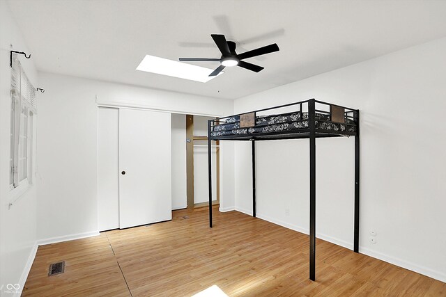 7642 Lancer Ln, Lawrence, IN 46226 - unfurnished bedroom with a skylight, light wood finished floors, baseboards, and ceiling fan