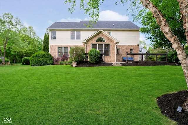 rear view of property with a yard, brick siding, and a deck