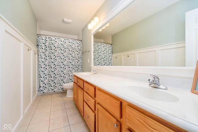 bathroom with tile patterned floors, toilet, double vanity, wainscoting, and curtained shower